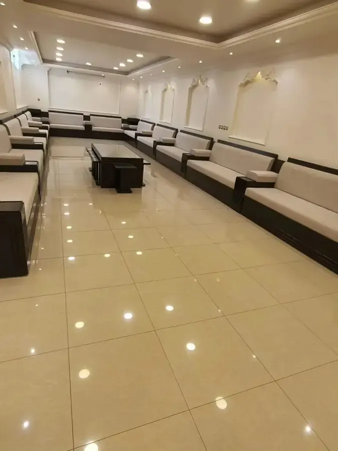 مجلس كنب رسمي بتنجيد أبيض على طول صالة طويلة مع طاولة وسط خشبية